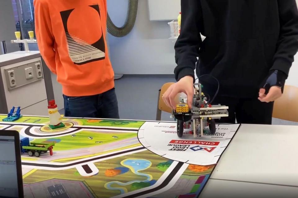 Zwei Teammitglieder der WGM Angels stellen in einem Video das Design ihres selbstgebauten LEGO-Roboters vor.