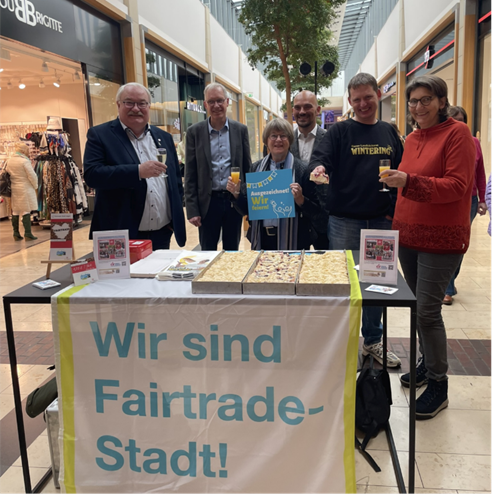 Bürgermeister Stefan Wittler, Holger Berentzen (Sprecher Fairtrade-Steuerungsgruppe), Maria Niemann (Sprecherin Fairtrade-Steuerungsgruppe), Patrick Stürmer (Centermanagement), Daniel Wintering (Bäckerei Wintering) und Uta van Roje (Weltladen)