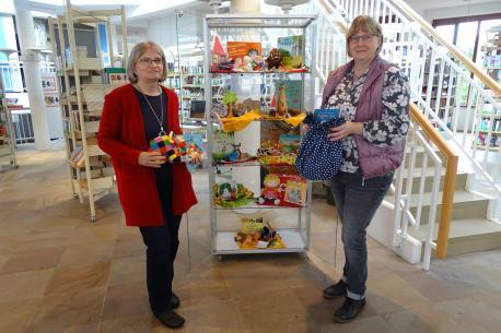 Annette Mansel (links) und Mechthild Jansen präsentieren die neuen Geschichtensäckchen und Erzählrucksäcke, die ab sofort in der Lingener Stadtbibliothek ausgeliehen werden können.