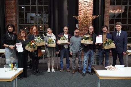 Oberbürgermeister Dieter Krone (re.) und Irene Vehring, die Vorsitzende des Kulturausschus-ses (li.) gratulieren den Kulturpreisträgerinnen und Kulturpreisträgern 2022: (v. li.) Irina Kemp-el, Nina Boldt, Barbara Sadeghi, Werner Schwegmann, Ebi Sadeghi, Pete Budden sowie Bri-an Lüken. 