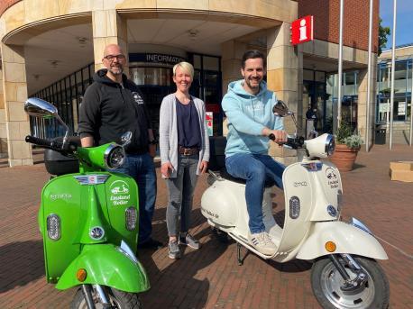 Maik Pingel von Emsland Roller übergibt vor der Lingener Tourist Info zwei Fahrzeuge an Natascha Meyer und Jan Koormann von der Lingen Wirtschaft und Tourismus GmbH.