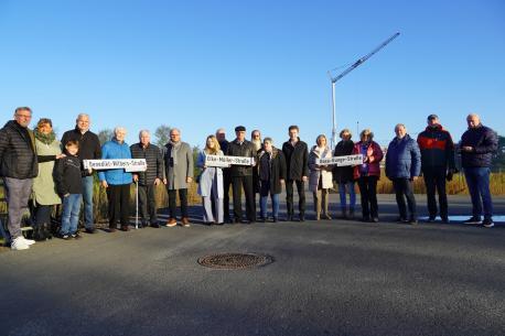Drei besondere Persönlichkeiten werden durch die Straßenbenennung im Baugebiet Hessenweg geehrt. Oberbürgermeister Dieter Krone präsentiert mit Familienangehörigen und Vertretern aus Politik die Schilder: Rosa-Bunge-, Elke-Müller- und Benedikt-Wilbers-Straße.