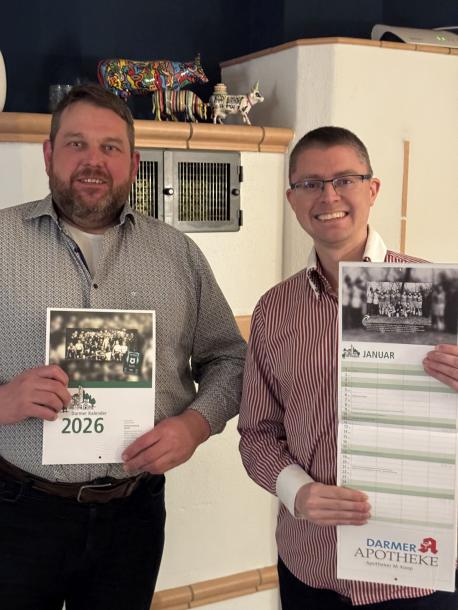Der Darmer Ortsbürgermeister Christoph Stafflage (links) und Simon Göhler halten den neuen Darmer Jahreskalender 2026 in den Händen.