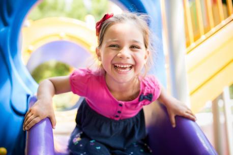 Kleines Mädchen, das draußen am Spielplatz im Sommer spielt