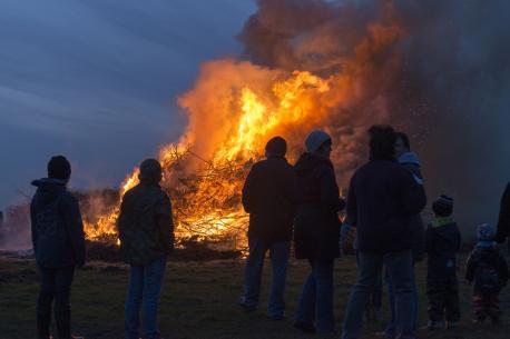 Erwachsene und Kinder stehen um ein Osterfeuer.