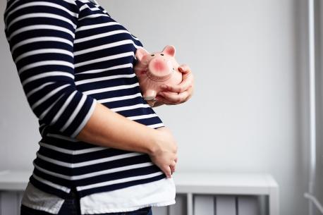 Schwangere Frau mit einem rosa Sparschwein