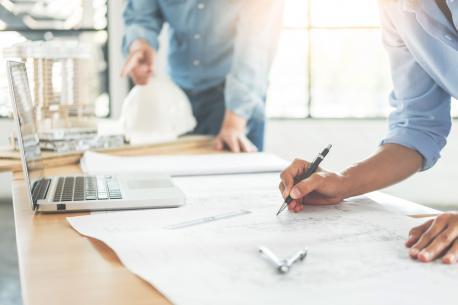 Architekten, die am Arbeitsplatz Pläne bearbeiten.