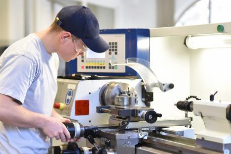 Technische Berufsausbildung: junger Auszubildender an der Drehbank einer C_NC Maschine