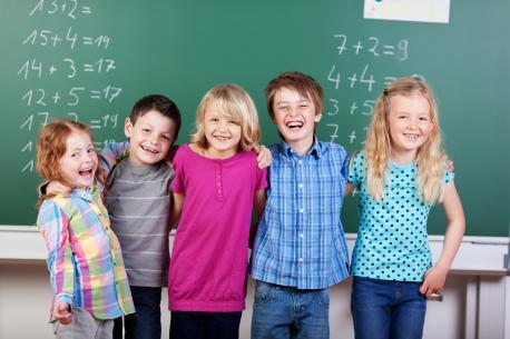 Lachende Schulkinder vor der Tafel