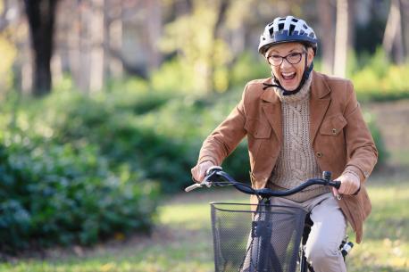 Das Bild zeigt eine Frau im mittleren Alter die euphorisch Fahrrad fährt