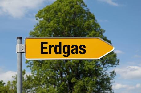Das Bild zeigt ein gelbes Schild in Form eines Pfeiles, der nach rechts zeigt, wo im Schild Erdgas steht. Im Hintergrund ist ein blauer Himmel mit einem Baum zu sehen.
