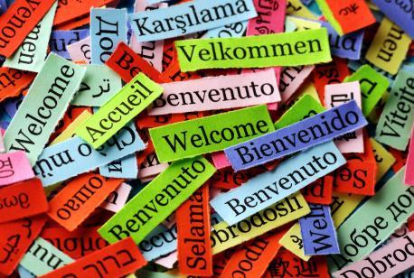 Das Bild zeigt ganz viele bunte unordentlich auf und neben einander liegende Papierzettel, wo auf jedem Zettel in einer anderen Sprache, dass Wort 
