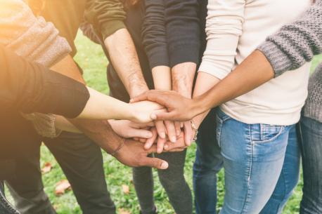 Multikulturelle Gruppe von Freunden, die Hände aufeinandergelegt haben; Teamwork