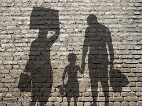 Schattenbild einer Flüchtlingsfamilie auf einer alten Mauer