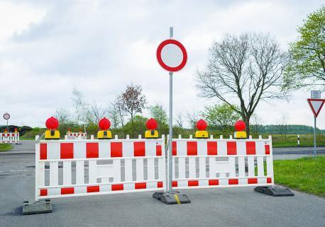 Absperrung auf einer Straße; rot-weiße Absperrzäune und ein 