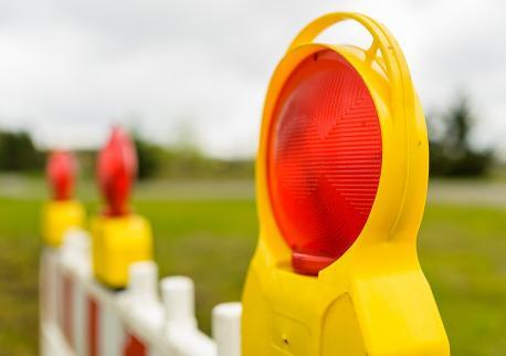 Rote Baustellen-Warnleuchten auf Absperrzäunen